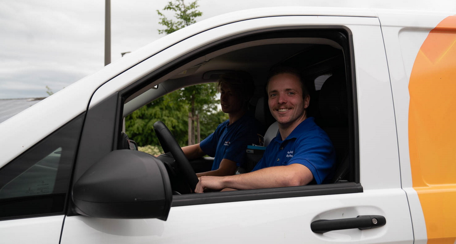 Servicetechniker Elektro Kessler lächelt aus Auto heraus
